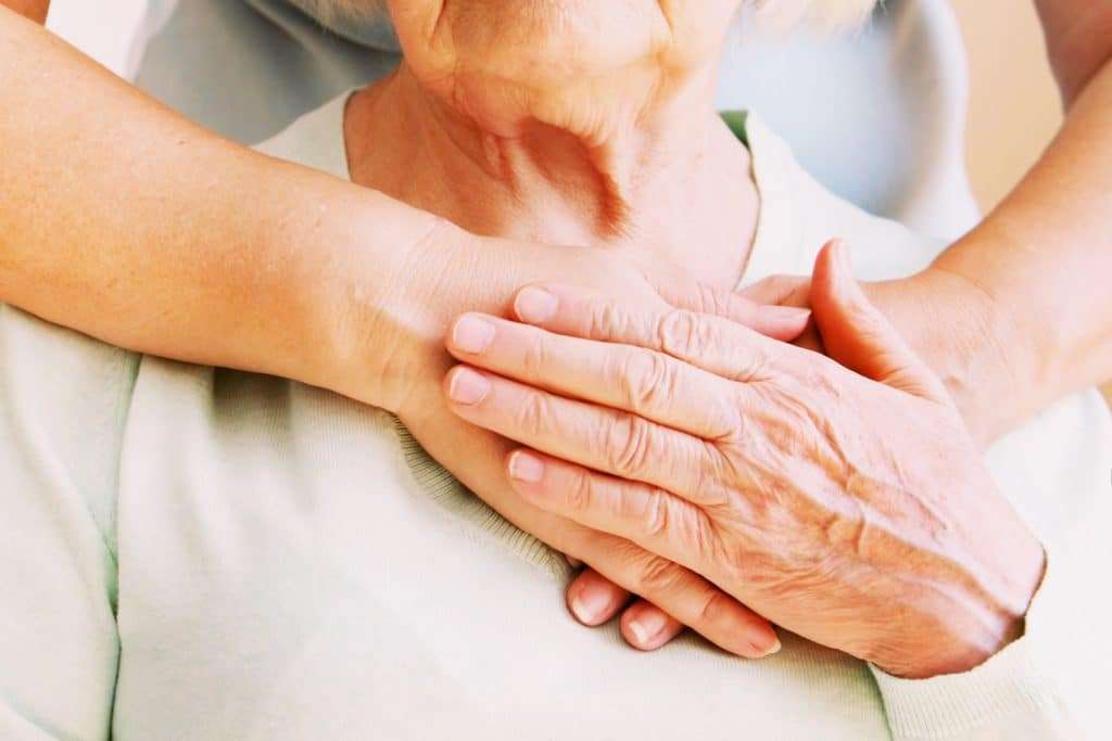 A woman with her hands around an elderly patient.