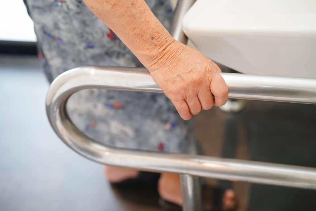 Top 8 Features to Look For in Tubs for Seniors 1 An elderly person using a handrail in the bathroom. Accesibility is an important feature for tubs for seniors.