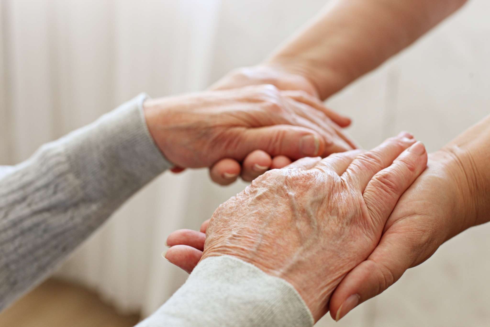 An elderly resident and caregiver holding hands in a long-term care facility