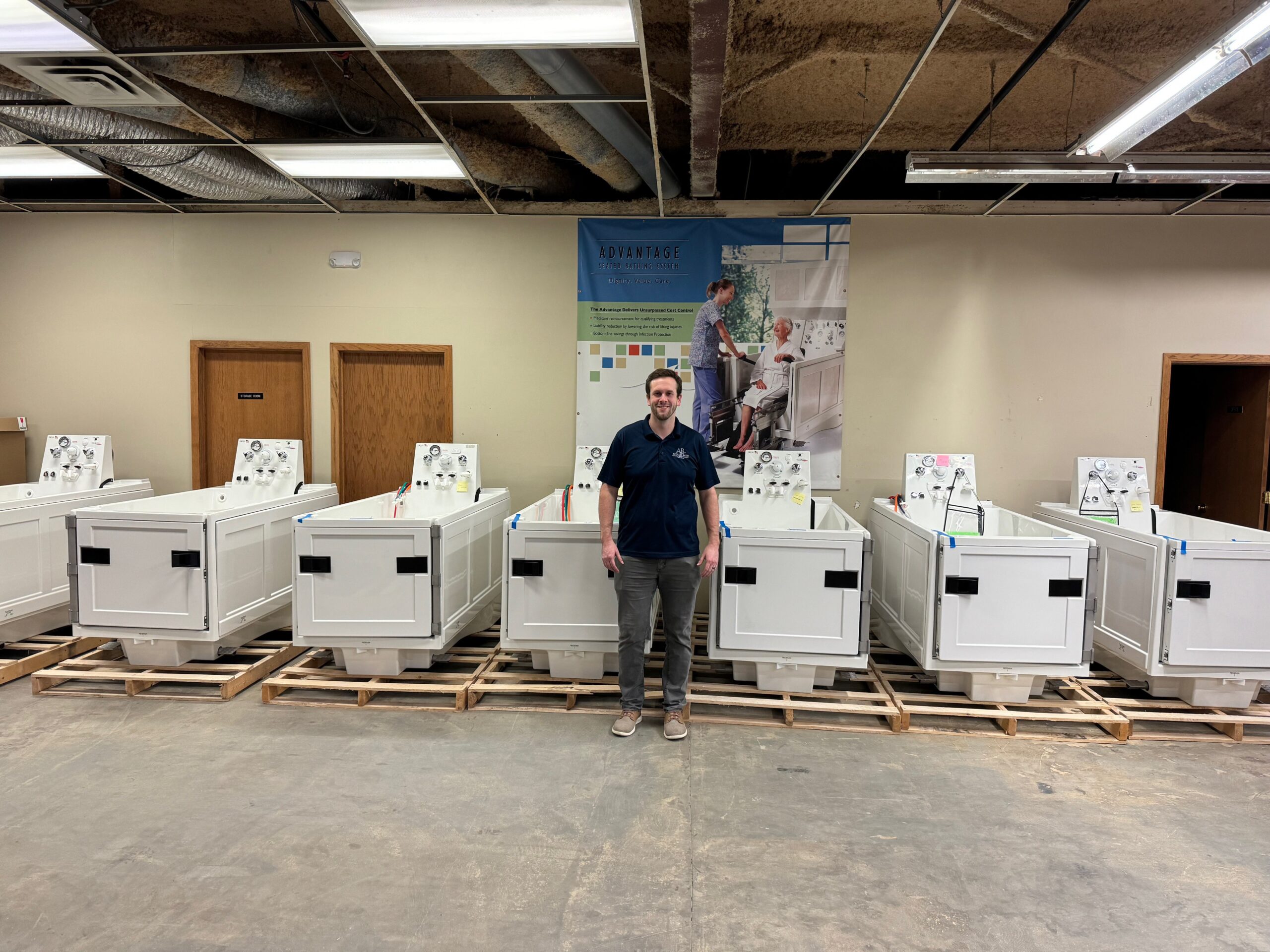 Our Team 5 Apollo Bath team member in front of a selection of hydrotherapy tubs, senior bath solutions